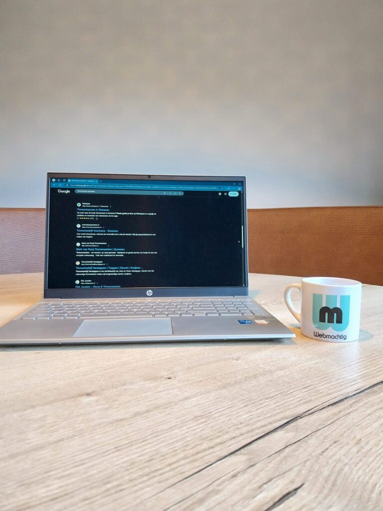 Laptop met zoekresultaten naast een mok met het Webmachtig-logo